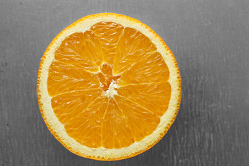 Half an orange with uneven slices on a tin background