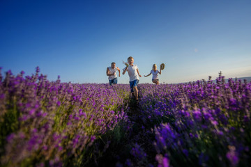 Happy family in a field of lavender on sunset.