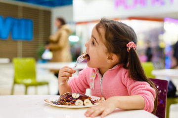 toddler girl eating in outdoor cafe