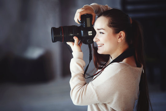Сute girl takes pictures with a professional camera