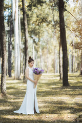 Portrait of Asian bride in a white lace wedding dress holding a bouquet.