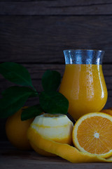 Fresh oranges with green leaf and juice in glass on wooden plate and wooden wall background  / Selective focus and Still life Image.