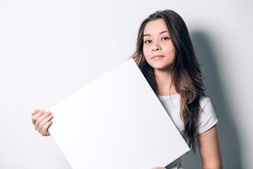 young smiling woman holding a blank sheet of paper for advertising.