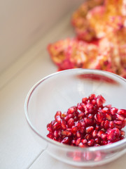 Close up to pomegranate with peel off and seeds in a glass bowl