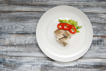 Fish Meat with Fresh Vegetables on White Plate over Gray Old Wooden Background with Copy Space.