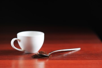 A spoonful of ground coffee lies on the table. Against the backdrop of a cup. Dark kitchen In a low key
