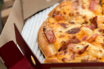 Close up of pizzas with variety of toppings and cheese in cardboard take out boxes with open lid