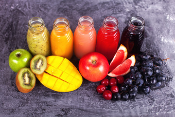 Fresh Color Juices Smoothie Violet Green Yellow Orange Red from Tropical Fruits Kiwi Water Melon Strawberry Apple Orange Banana Pine Apple Mango Pomegranate Grape Bottles Rainbow Dark Background