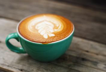 Cappuccino coffee in a green cup on wooden