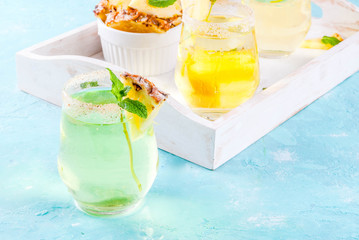 Tropical drink,  Pineapple  juice margarita cocktail with fresh mint, light blue background, wooden tray, copy space