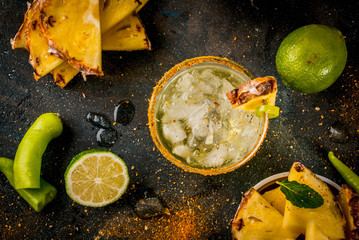 Mexican beverage, spicy margarita cocktail with pineapple and jalapeno and lime, dark blue...