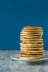 Stack of pancakes with honey on blue background