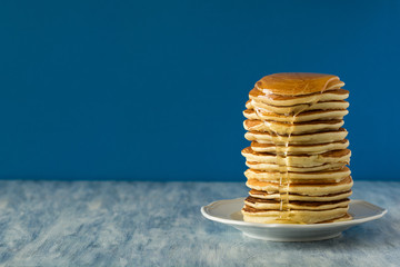 Stack of pancakes with honey on blue background