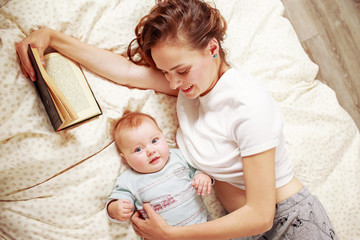 Mother reading a book while holding a baby