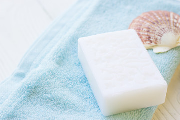 Natural Sea Spa Elements on white wooden background.White and blue clean towels, hand made natural soap and sea shells