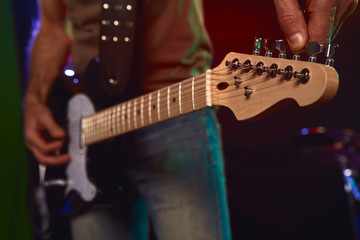 The guitarist tunes the guitar.