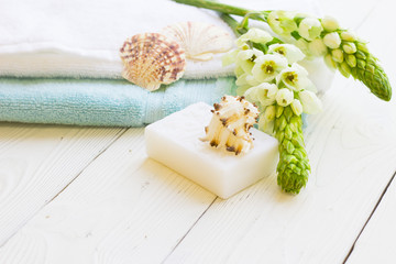 Fototapeta na wymiar Natural Sea Spa and aromatherapy concept with blue and white towels, hand made soap, sea shells and fresh white flowers on a white wooden background