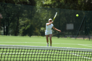 blurred woman playing tennis in a green field