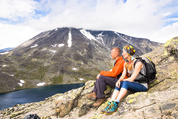 Sport couple hiking on Besseggen. Hikers enjoy beautiful lake and good weather in Norway.