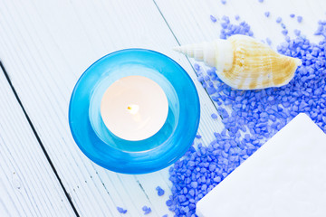 Spa Treatment Concept mock up with natural lavender bath salt, an aroma candle in a blue candle holder, a bar of soap and sea shell on a white wooden table , top view