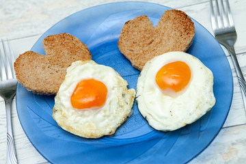 Fried eggs with toast in the shape of heart for love breakfast