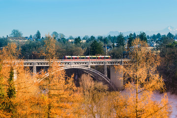 The train is sailing on a river bridge with a back view of the Alps in Bern, Switzerland.