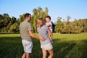 Happy family in nature. Parents with a child play in park.