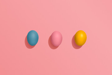 Colorful Easter Eggs on pink coloured background, fun Easter flat lay with copy space 