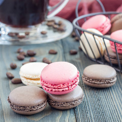 Different kinds of colorful french dessert macaron with different fillings on wooden table, served with coffee, square