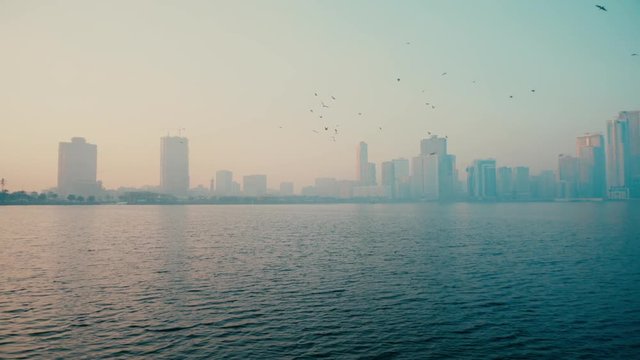 Urban background, morning cityscape with skyscrapers, blue sky reflecting in blue sea and big metropolis.