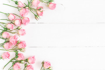 Flowers composition. Frame made of pink rose flowers on white wooden background. Flat lay, top view, copy space - obrazy, fototapety, plakaty