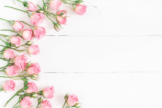 Flowers composition. Frame made of pink rose flowers on white wooden background. Flat lay, top view, copy space