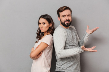 Portrait of a confused young couple standing back to back