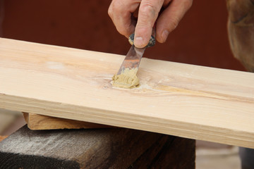 Putty knife in old man's hand. Removing paint from a wood surface. Preparation of boards before...