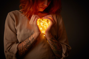 Woman holding lights in the shape of a heart - Powered by Adobe
