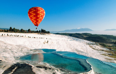 Hot air balloon flying over Travertine pools limestone terraces in Pamukkale, Denizili, Turkey