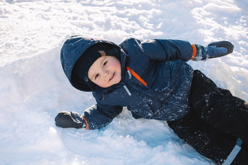 little boy in blue jacket  play with snow, winter holidays