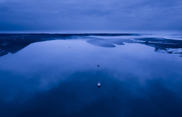 Aerial view of sailboats and bridge at night in fog.