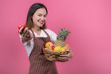 Portrait of happy young woman asian holding fruits basket while standing at studio.