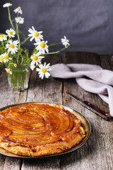 Traditional homemade banana caramel pie on vintage wooden table decorated a bouquet of chamomiles. Upside down banana cake. Selective focus 