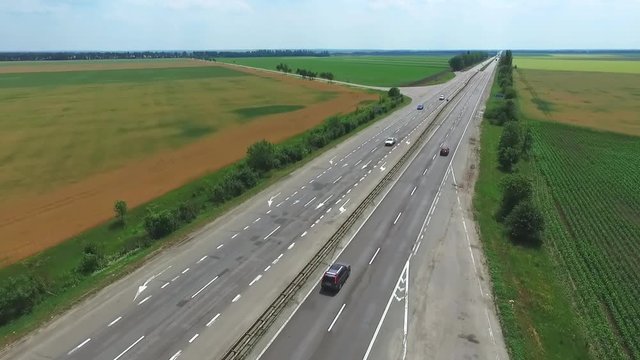 Aerial view of road highway traffic full HD video. Cars riding at farm rural field landscape background. 