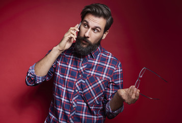Puzzled man talking by mobile phone at studio shot