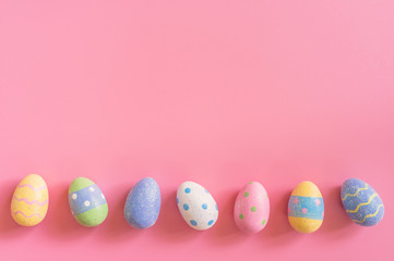 Colorful easter eggs on pink pastel color background with space.