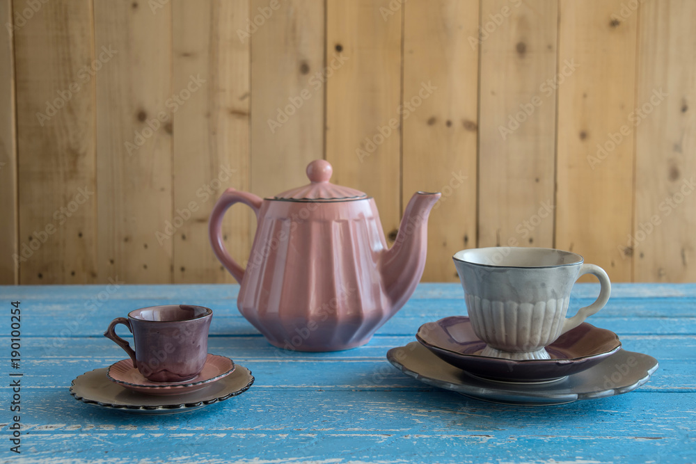 Wall mural teapot with teacup on wood background.