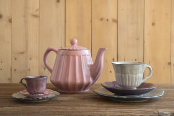 Teapot with teacup on wood background.