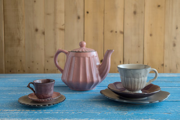 Teapot with teacup on wood background.
