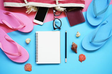 Top view of Travel accessories and blank notebook on pink and blue background with copy space.