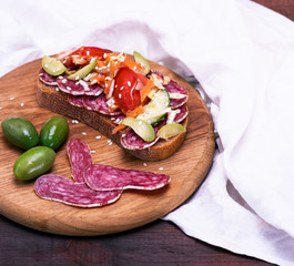 sandwich with smoked sausage and vegetables on a kitchen wooden board, top view