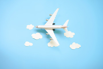 Flat lay design of travel concept with plane and cloud on blue background with copy space.