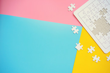 White jigsaw puzzle on blue, pink and yellow background.